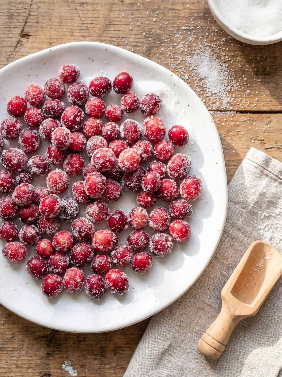 Sugared cranberries rolled in sugar on a plate.