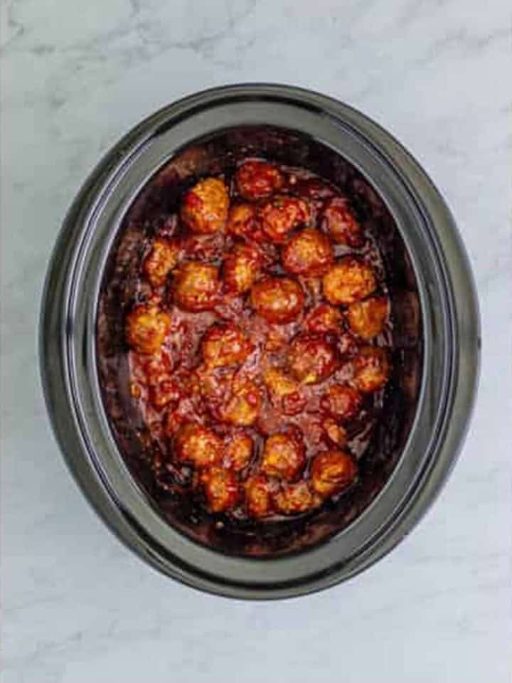 Cranberry Meatballs coated in sauce inside the slow cooker.