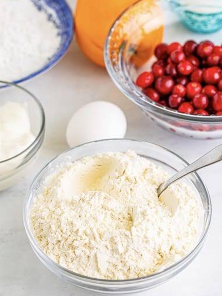 Stirring together the dry ingredients for Cranberry Orange Muffins in a glass bowl.