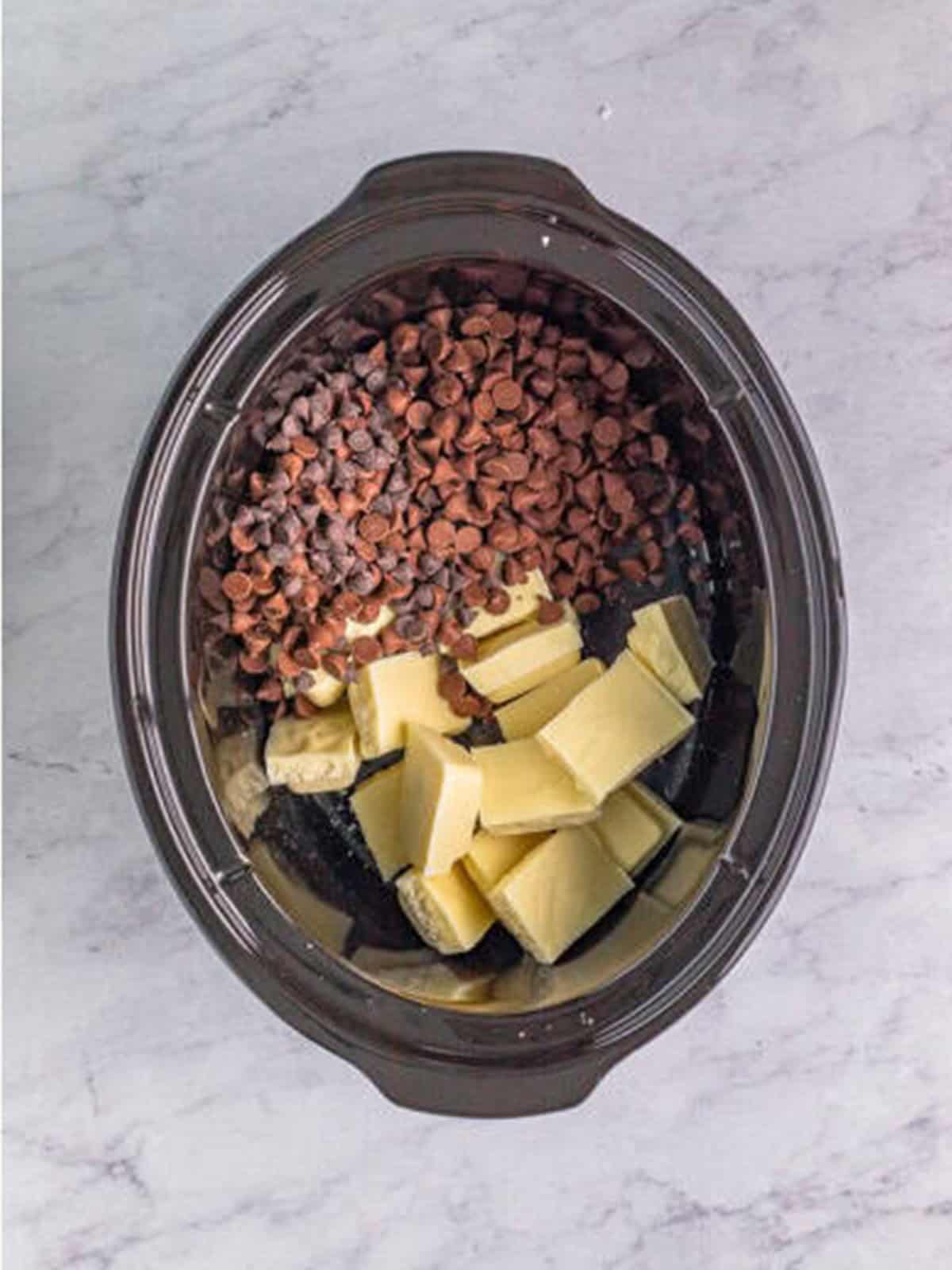 White melting chocolate, semi-sweet chips, and milk chocolate chips added to the slow cooker
