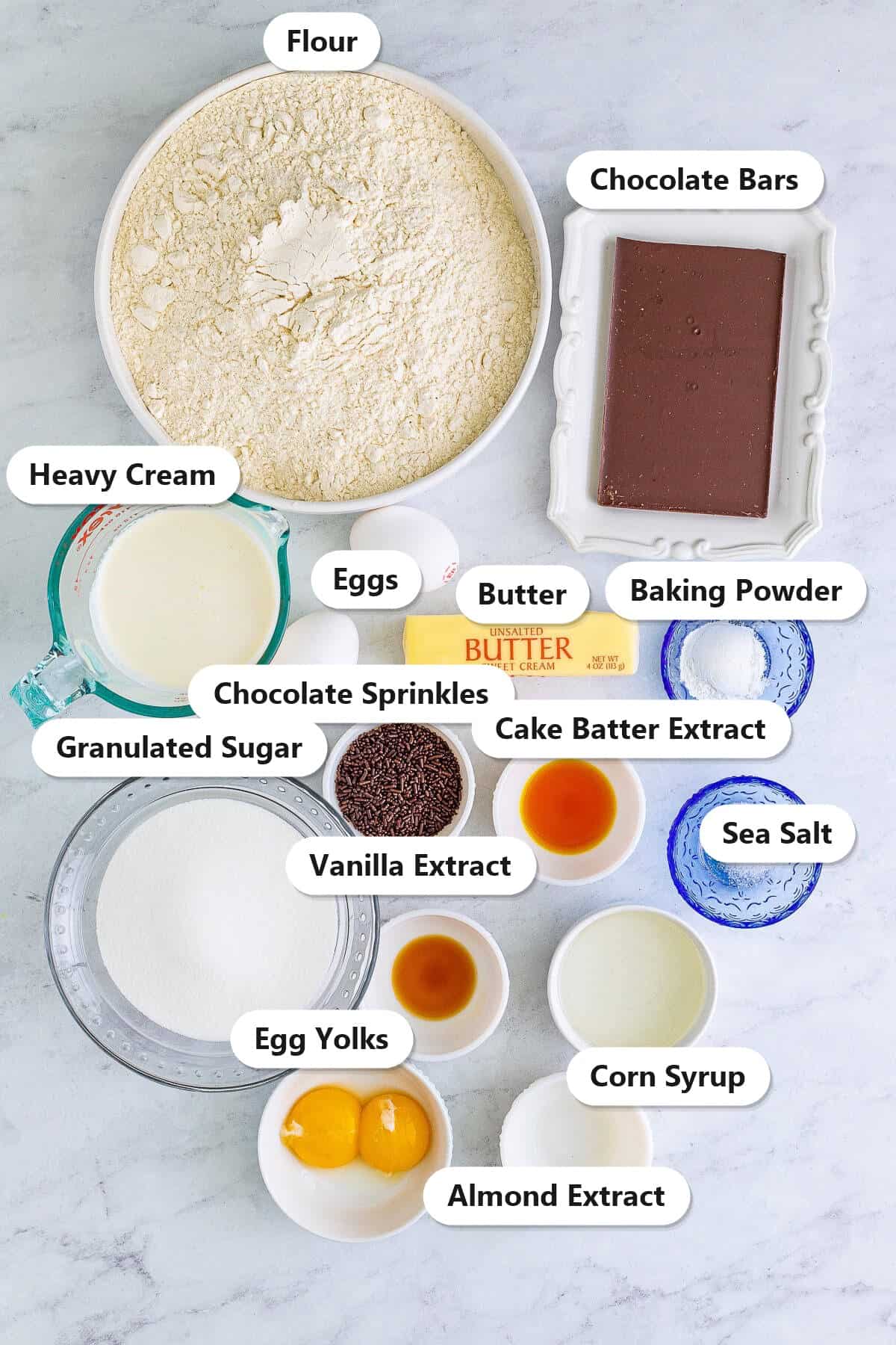 Crumbl Chocolate Cupcake Cookies ingredients laid out and labeled including flour, chocolate bars, heavy cream, butter, extracts, and sprinkles.
