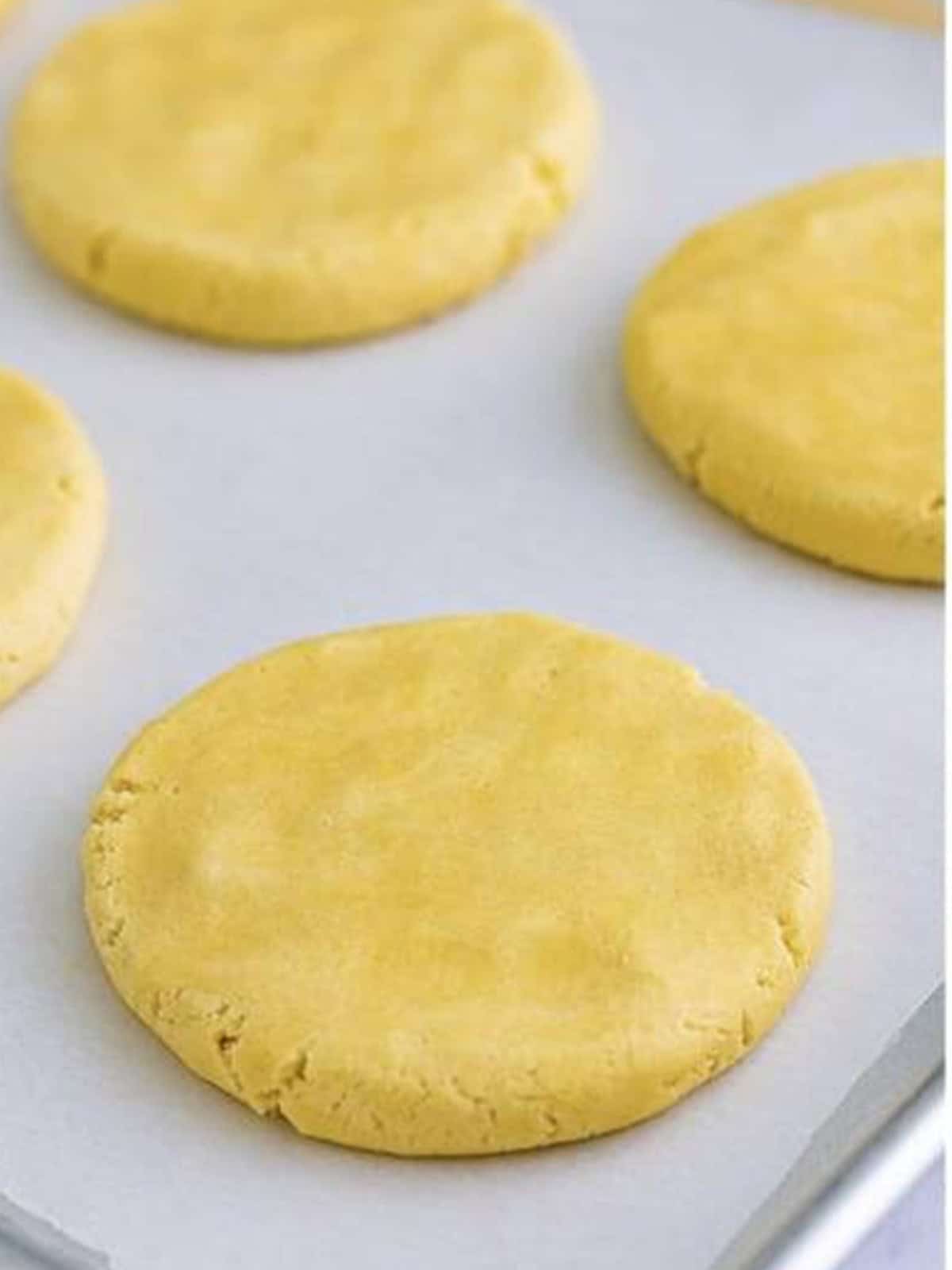 Dough balls pressed into large flat circles before baking.