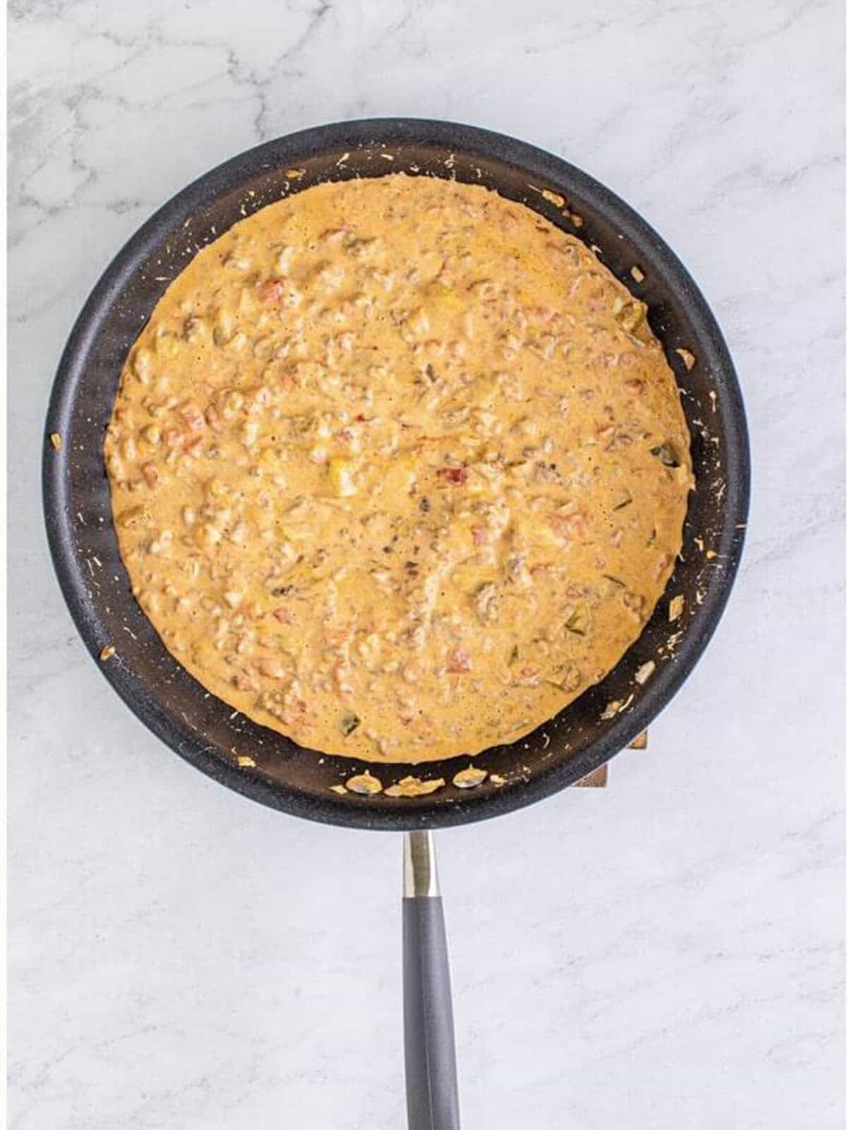 Fully melted and combined dill pickle cheeseburger dip in a skillet.