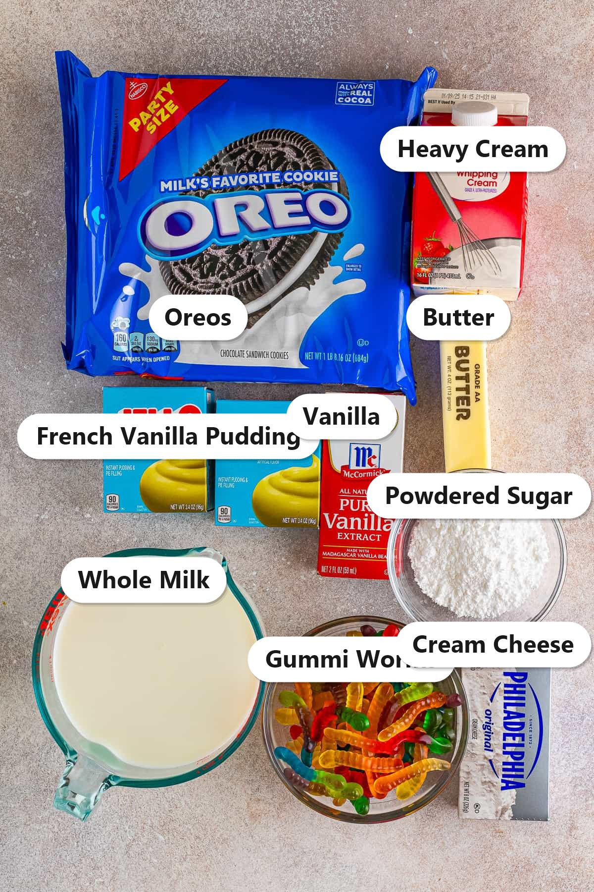 Labeled ingredients for dirt cake including Oreos, French vanilla pudding, cream cheese, heavy cream, whole milk, powdered sugar, butter, vanilla, and gummi worms.