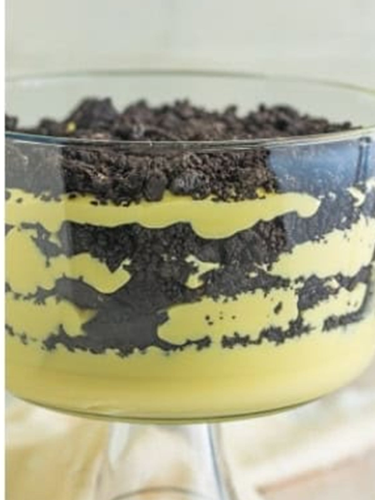 A trifle dish layered with pudding and crushed Oreos for no bake dirt cake.