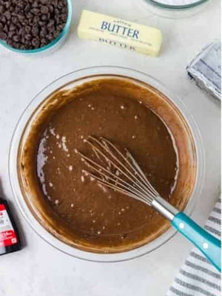 Chocolate cake batter whisked together in a glass mixing bowl.