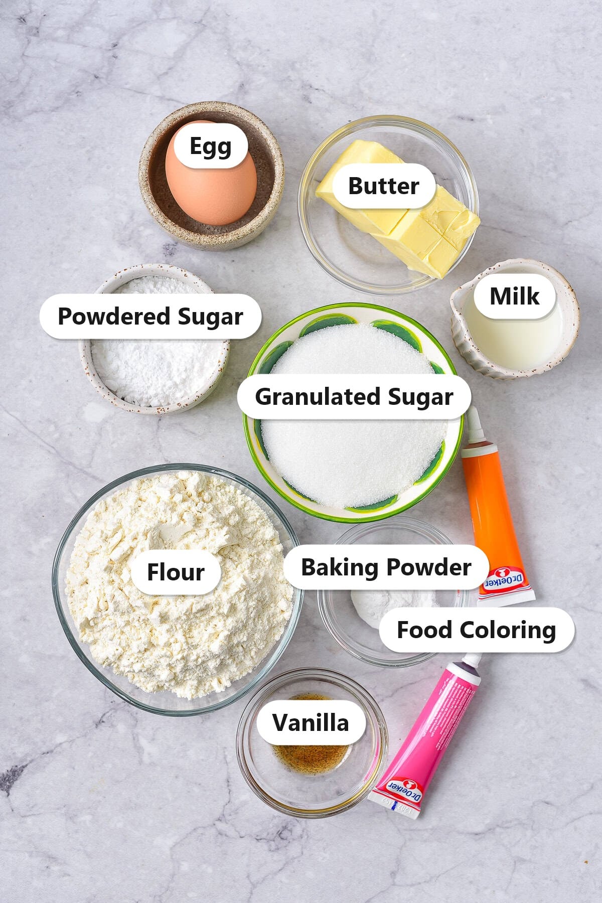Labeled ingredients for Easter bunny cookies including flour, cold butter, granulated sugar, powdered sugar, egg, milk, vanilla, baking powder, and food coloring.