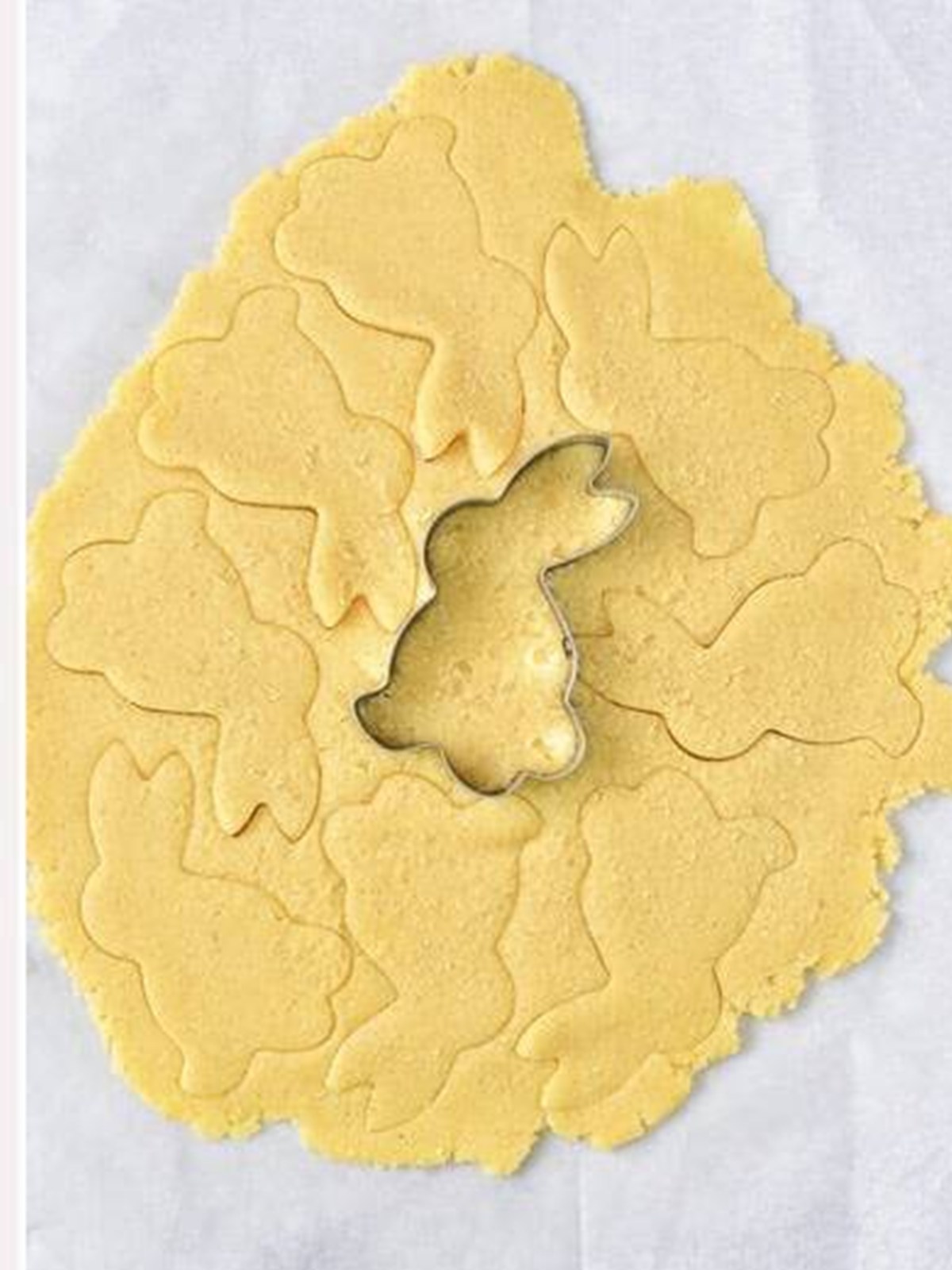 Cutting bunny shapes out of the rolled cookie dough with a bunny cutter.
