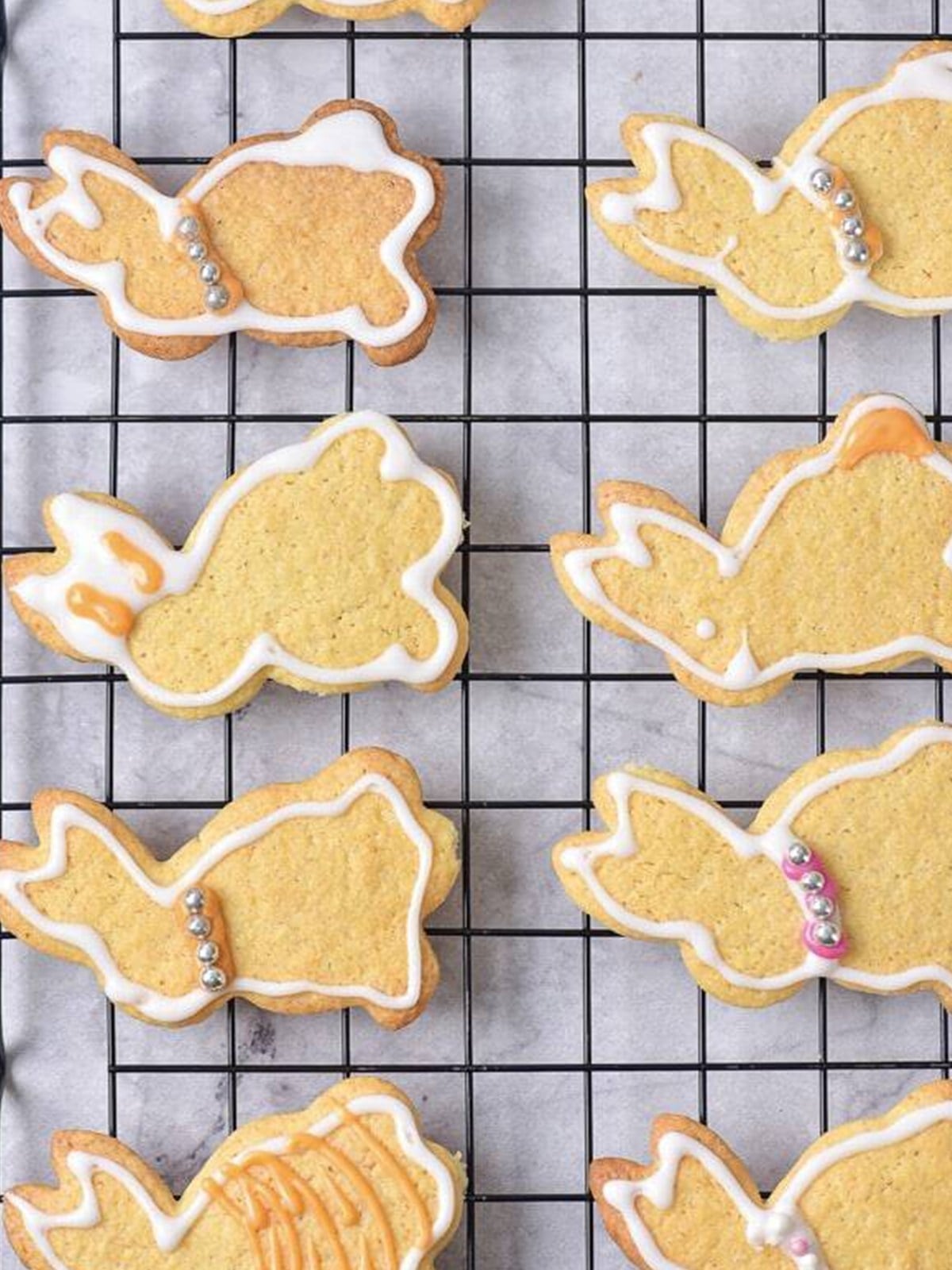 Decorated Easter bunny cookies with white glaze outlines drying on a wire rack.