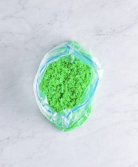 Coconut flakes dyed green with food coloring in a plastic bag.