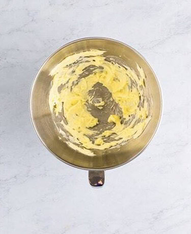 Butter whipped smooth in a stand mixer bowl for coconut frosting.