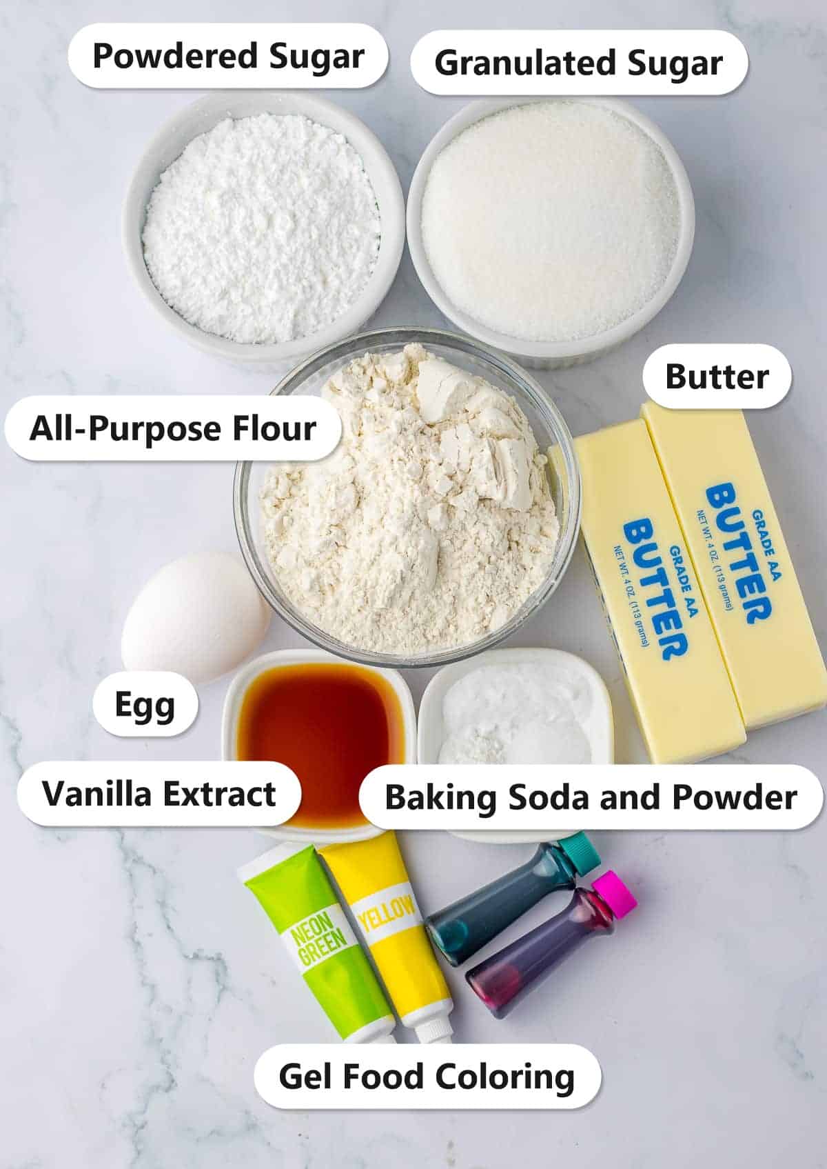 Labeled ingredients for Easter sugar cookies including flour, butter, granulated sugar, powdered sugar, egg, vanilla extract, baking soda and powder, and gel food coloring.