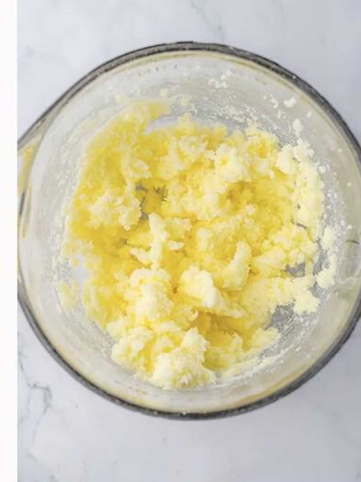 Butter and granulated sugar creamed together in a glass bowl until light and fluffy.