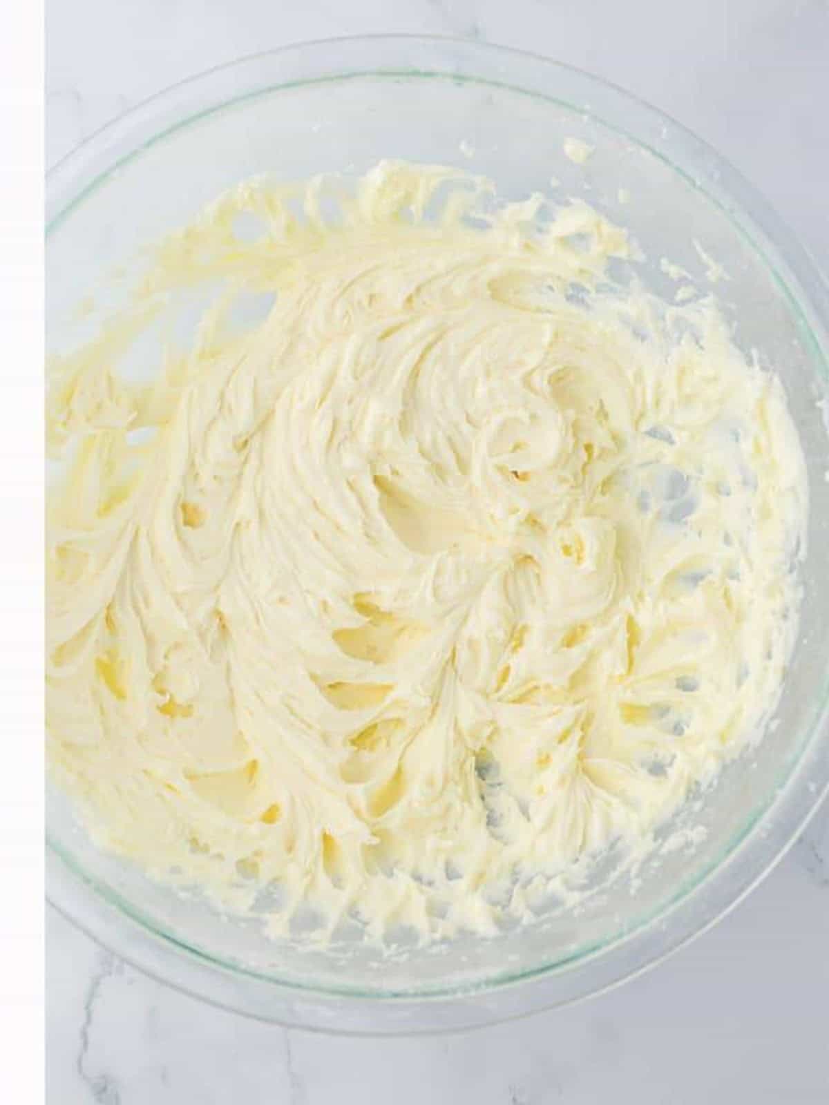 Whipped vanilla buttercream filling for Easter sugar cookie sandwiches in a glass bowl.
