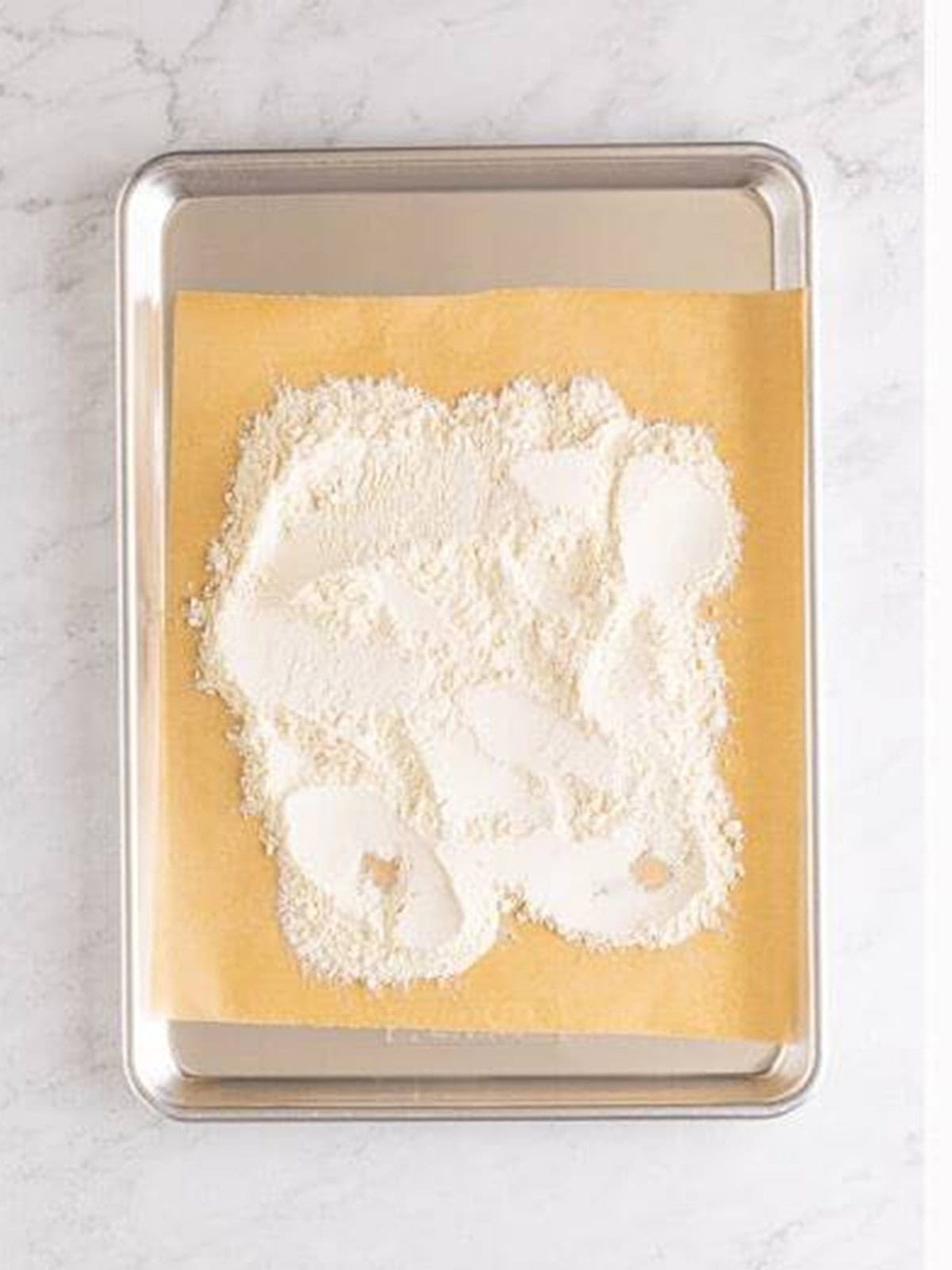 Flour spread on a sheet pan to heat treat it for edible cookie dough.