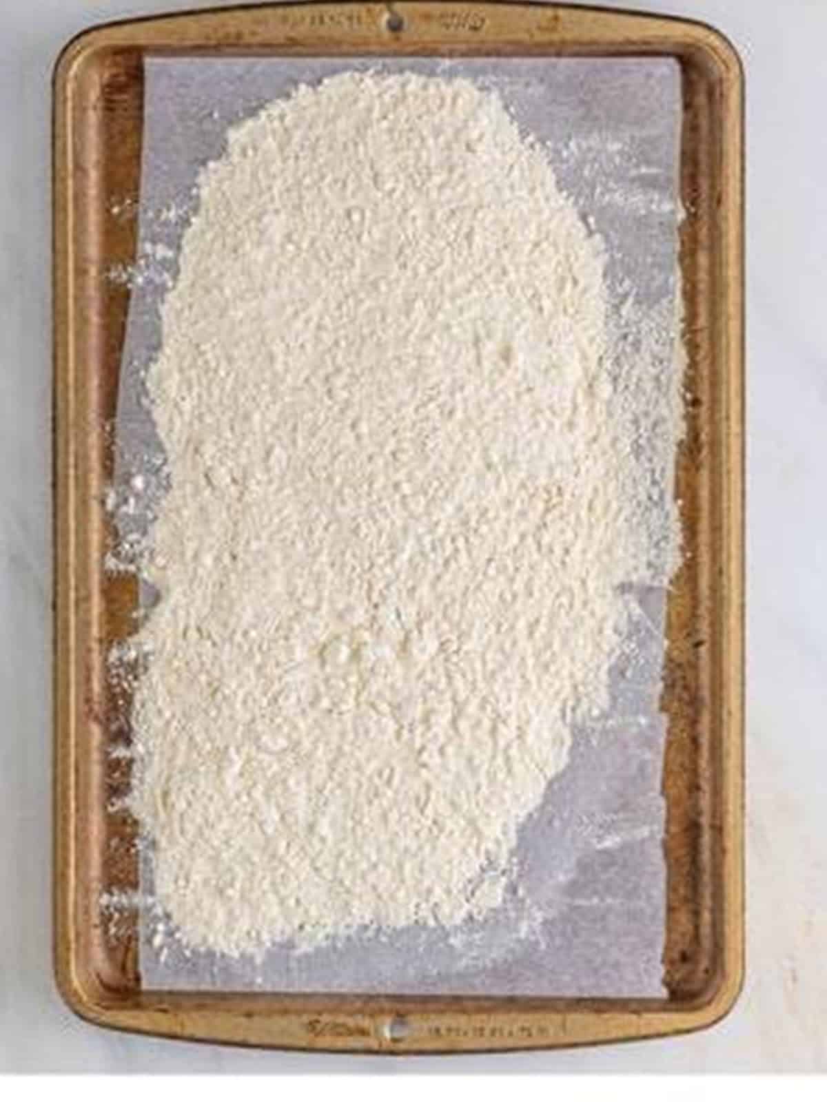 Toasted flour spread on a baking sheet for edible Snickerdoodle Cookie Dough.