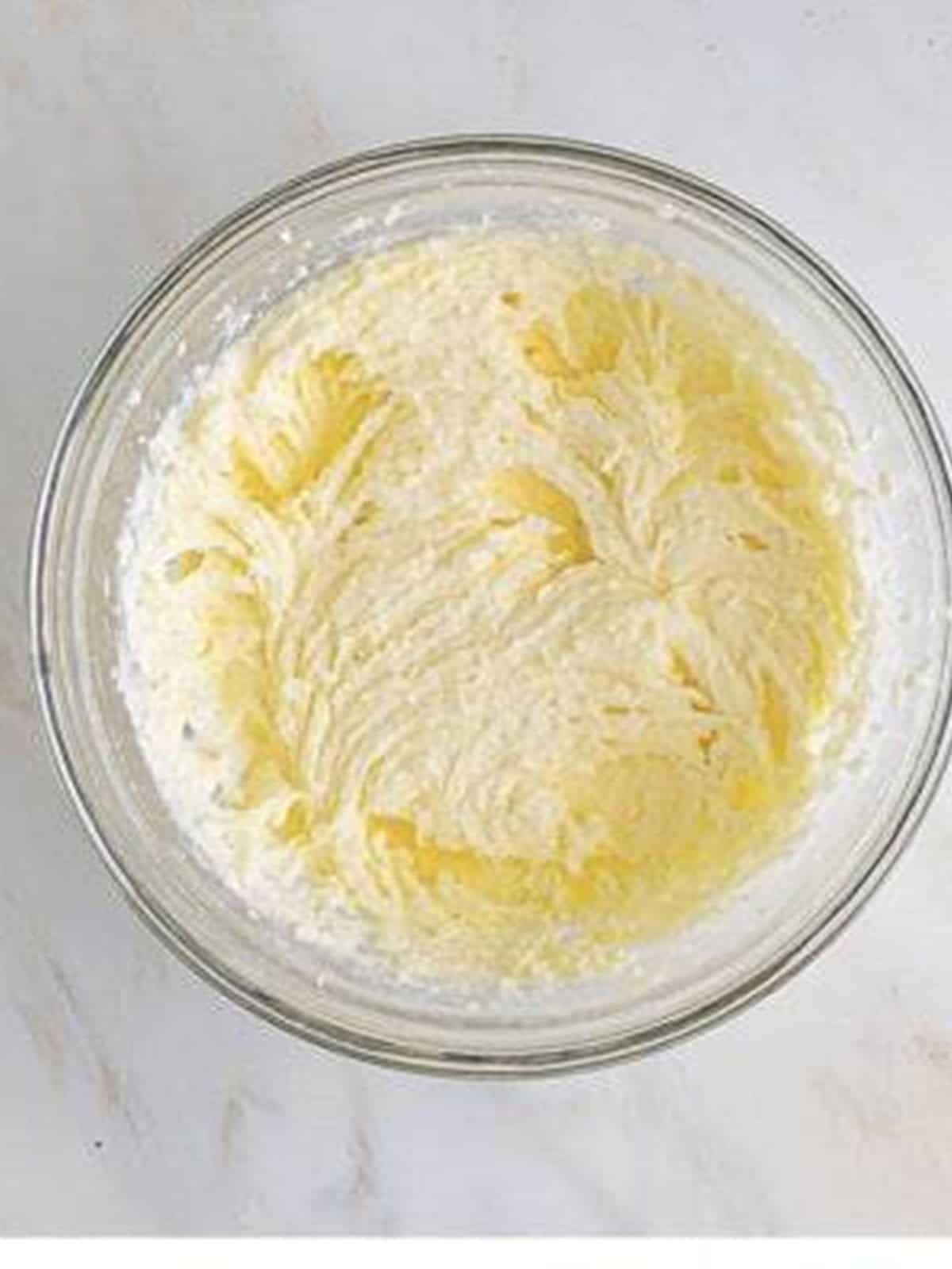 Powdered sugar being mixed into creamed butter and sugar.