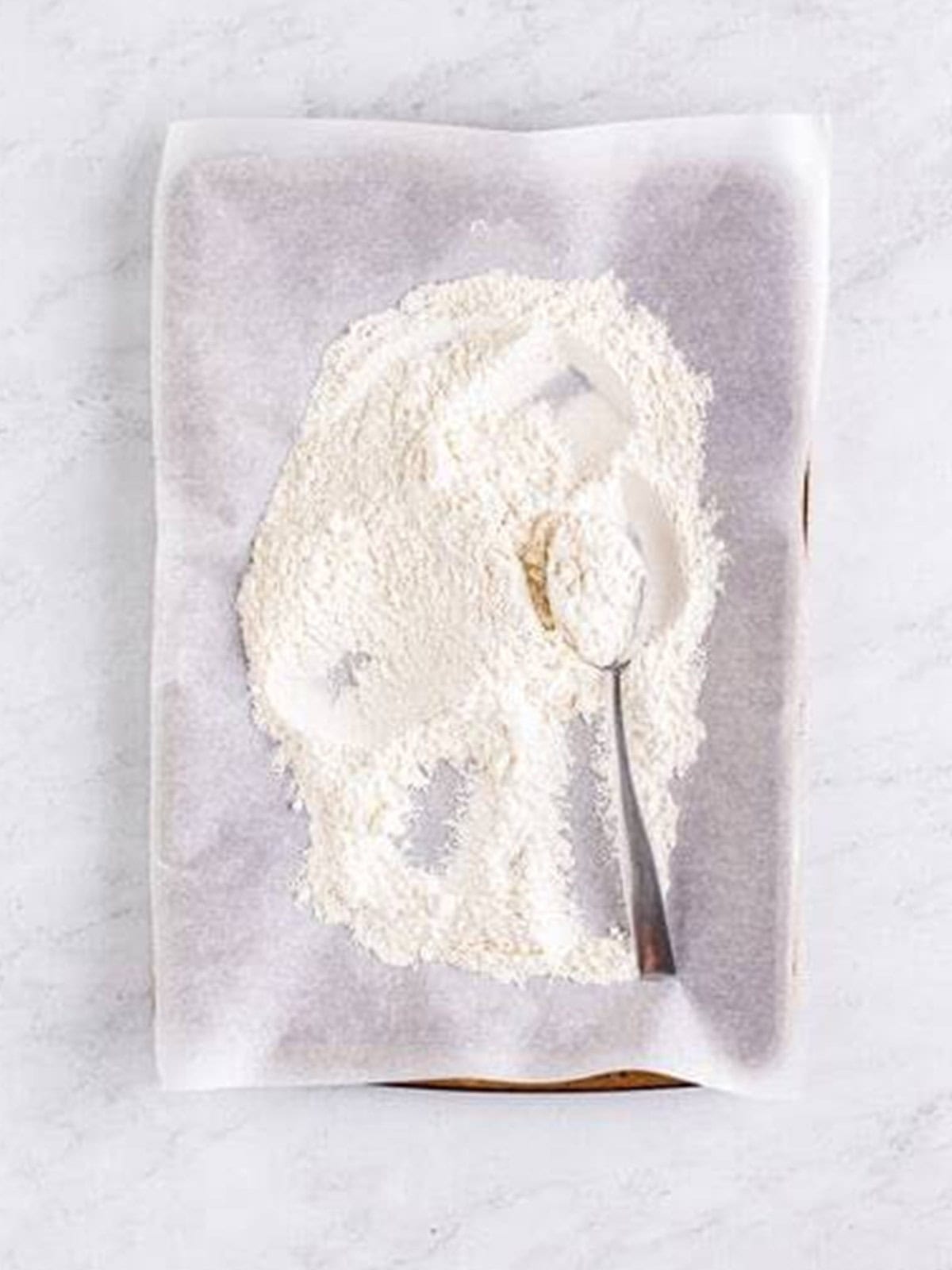 Heat treated flour spread on a parchment lined sheet tray for edible sugar cookie dough.
