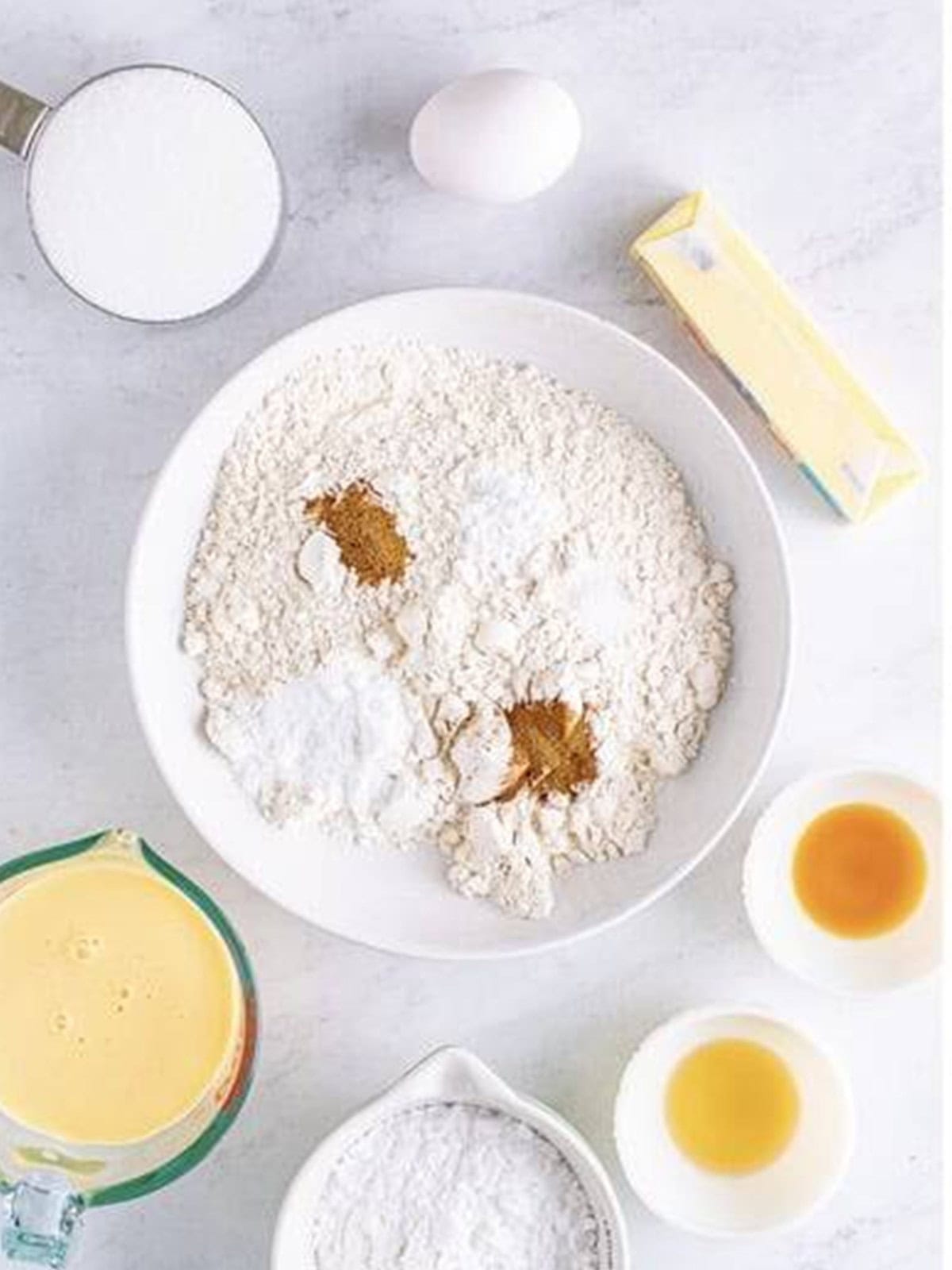 Flour, baking soda, baking powder, cinnamon, nutmeg, and salt in a mixing bowl for eggnog bread.