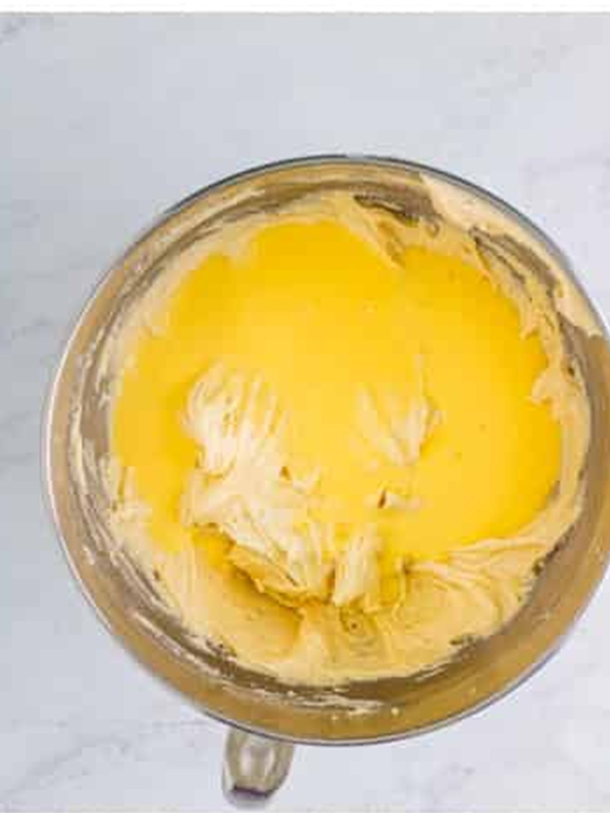 Pouring the eggnog into the cake batter in the stand mixer bowl.