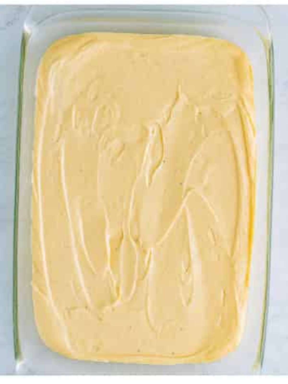 Eggnog cake batter spread evenly in a glass baking dish.