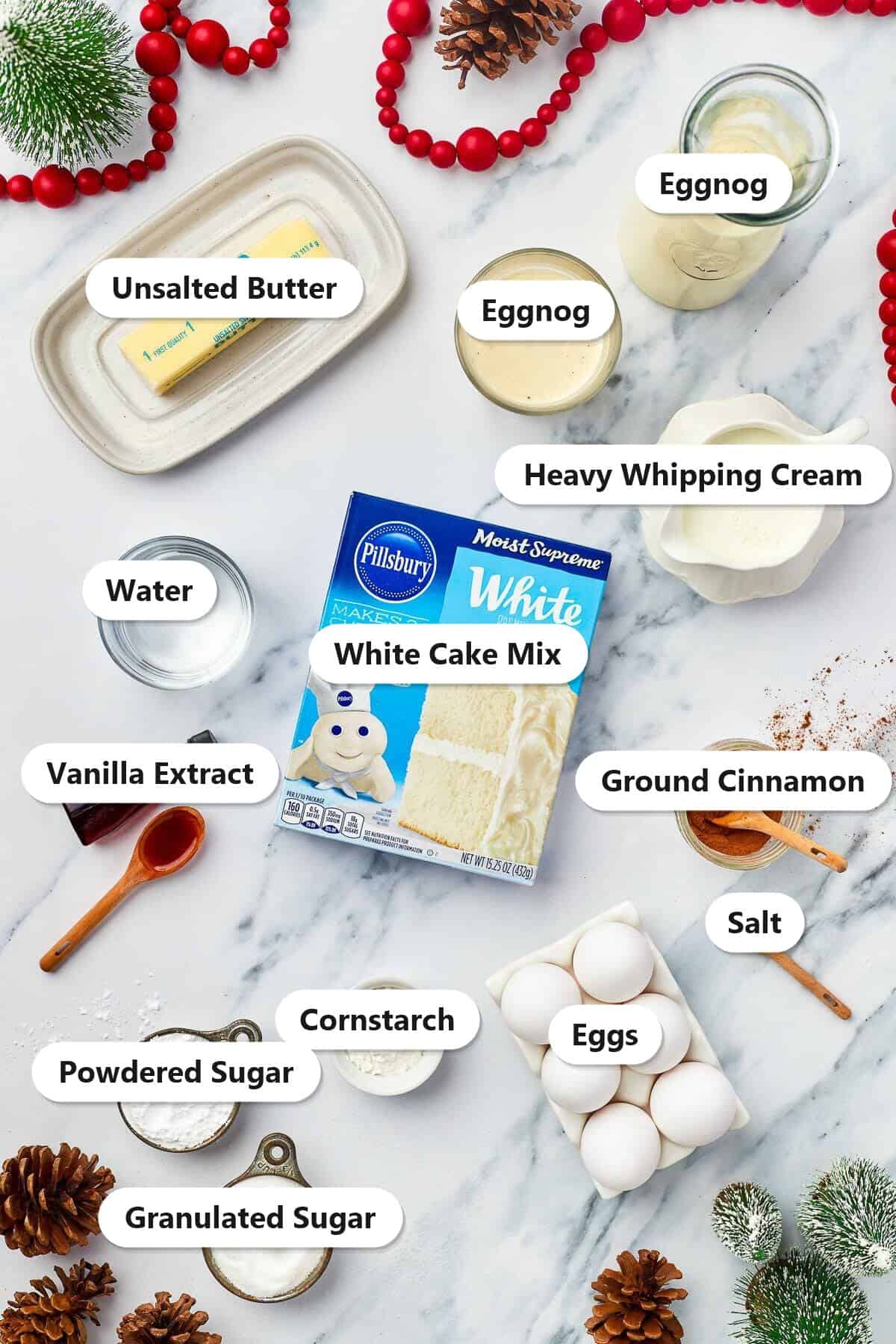 Labeled ingredients for eggnog cupcakes including white cake mix, eggnog, heavy whipping cream, butter, eggs, cinnamon, cornstarch, and sugars.