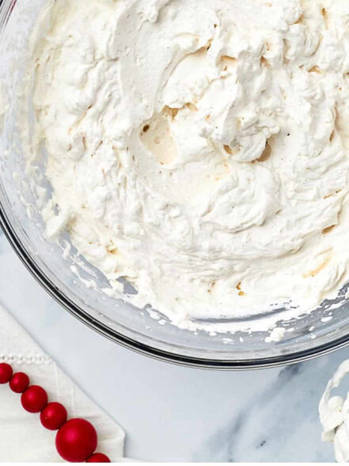 Cinnamon whipped cream beaten to stiff peaks in a glass bowl.