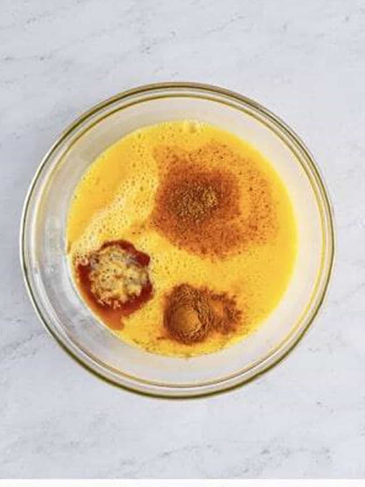 Eggnog, eggs, and spices in a bowl ready to whisk for eggnog french toast custard.