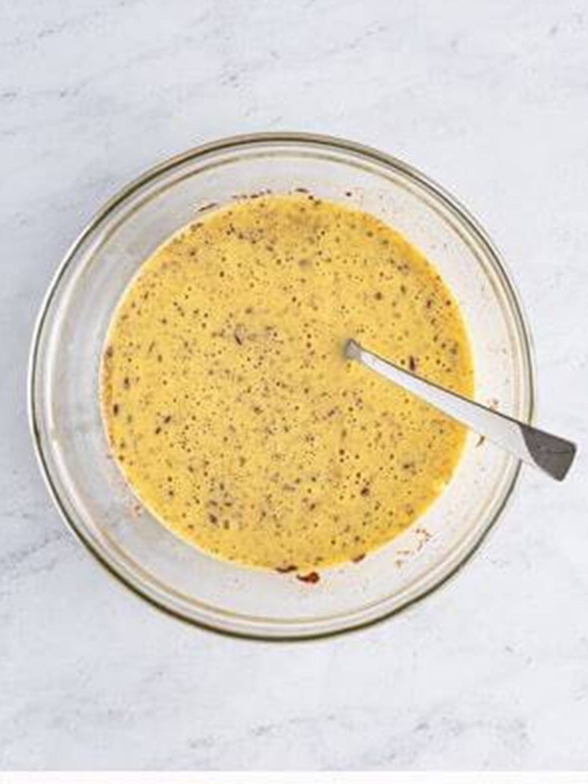 Eggnog custard whisked smooth in a glass bowl.