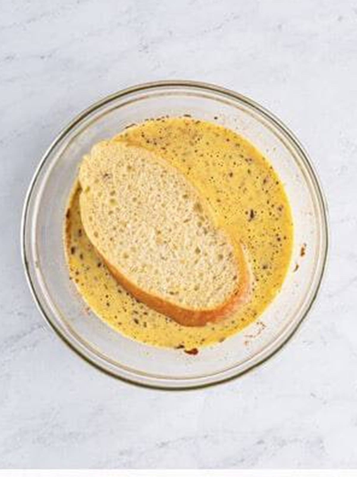 Thick slice of French bread ready to dip into the eggnog custard.