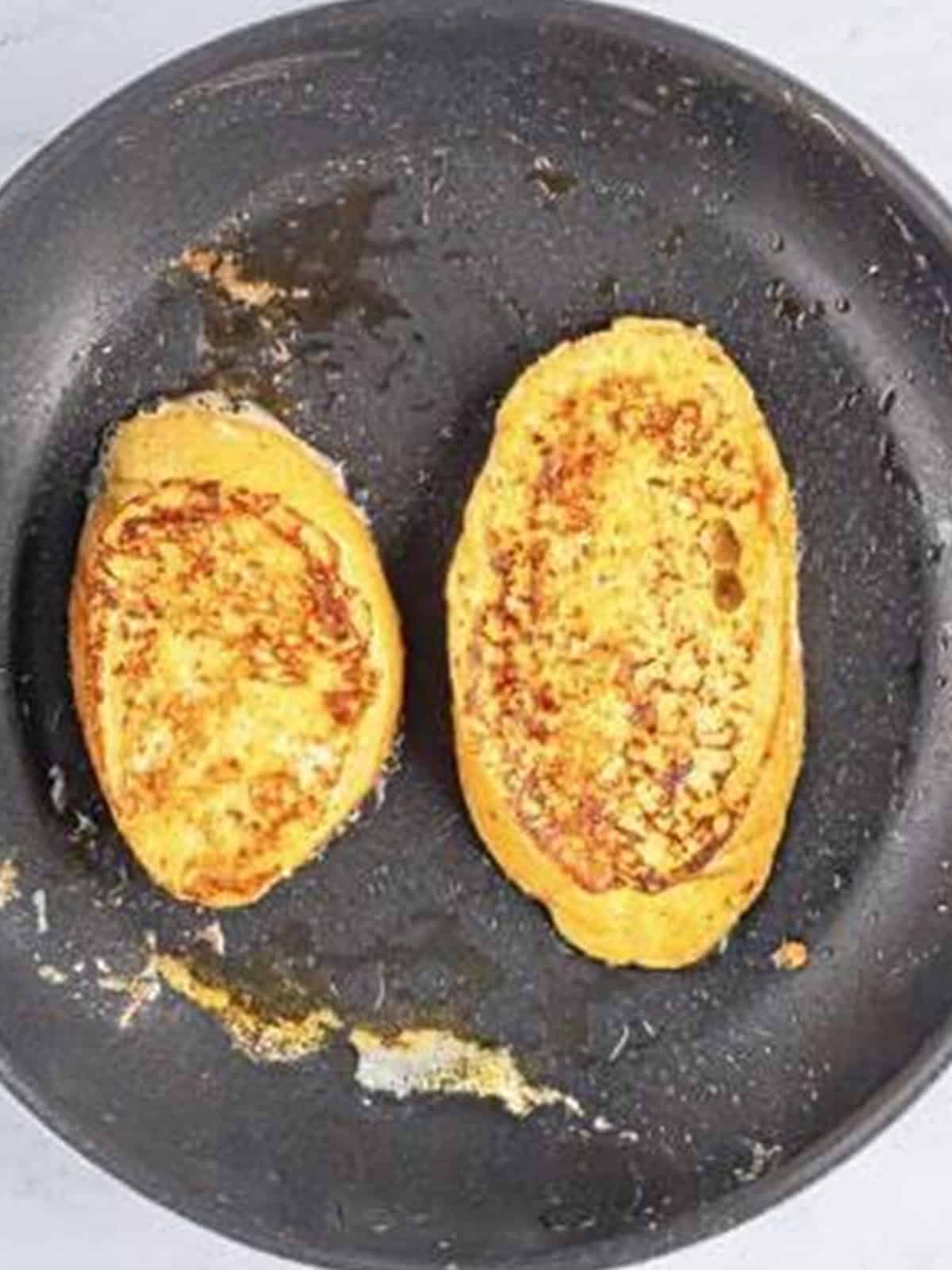 Eggnog french toast slices cooking golden brown in a buttered skillet.