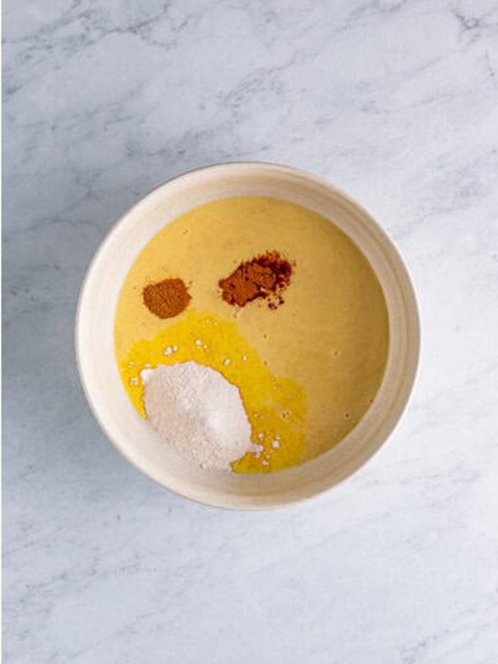 Vanilla pudding mix, eggnog, bourbon, Fireball, cinnamon, and nutmeg in a large bowl for eggnog pudding shots.
