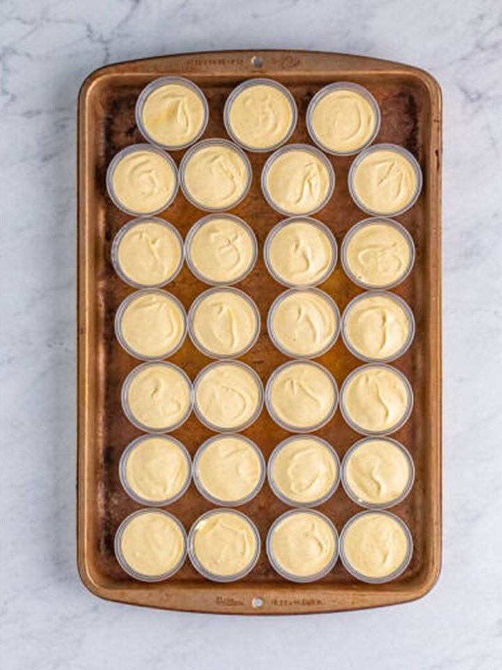 Two ounce cups on a sheet tray filled with the eggnog pudding shot mixture.