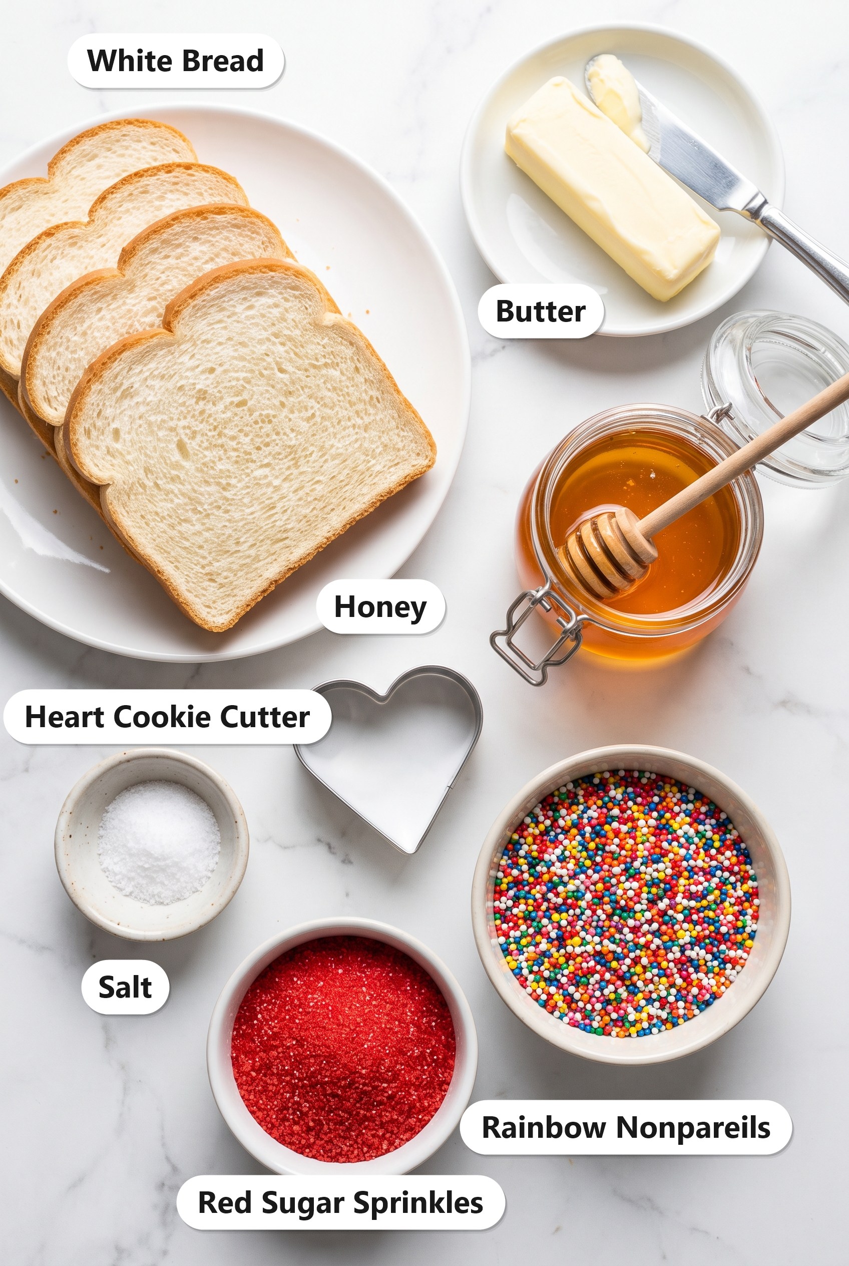 Labeled ingredients for Fairy Bread including white bread, butter, honey, salt, rainbow nonpareils, red sugar sprinkles, and a heart cookie cutter.