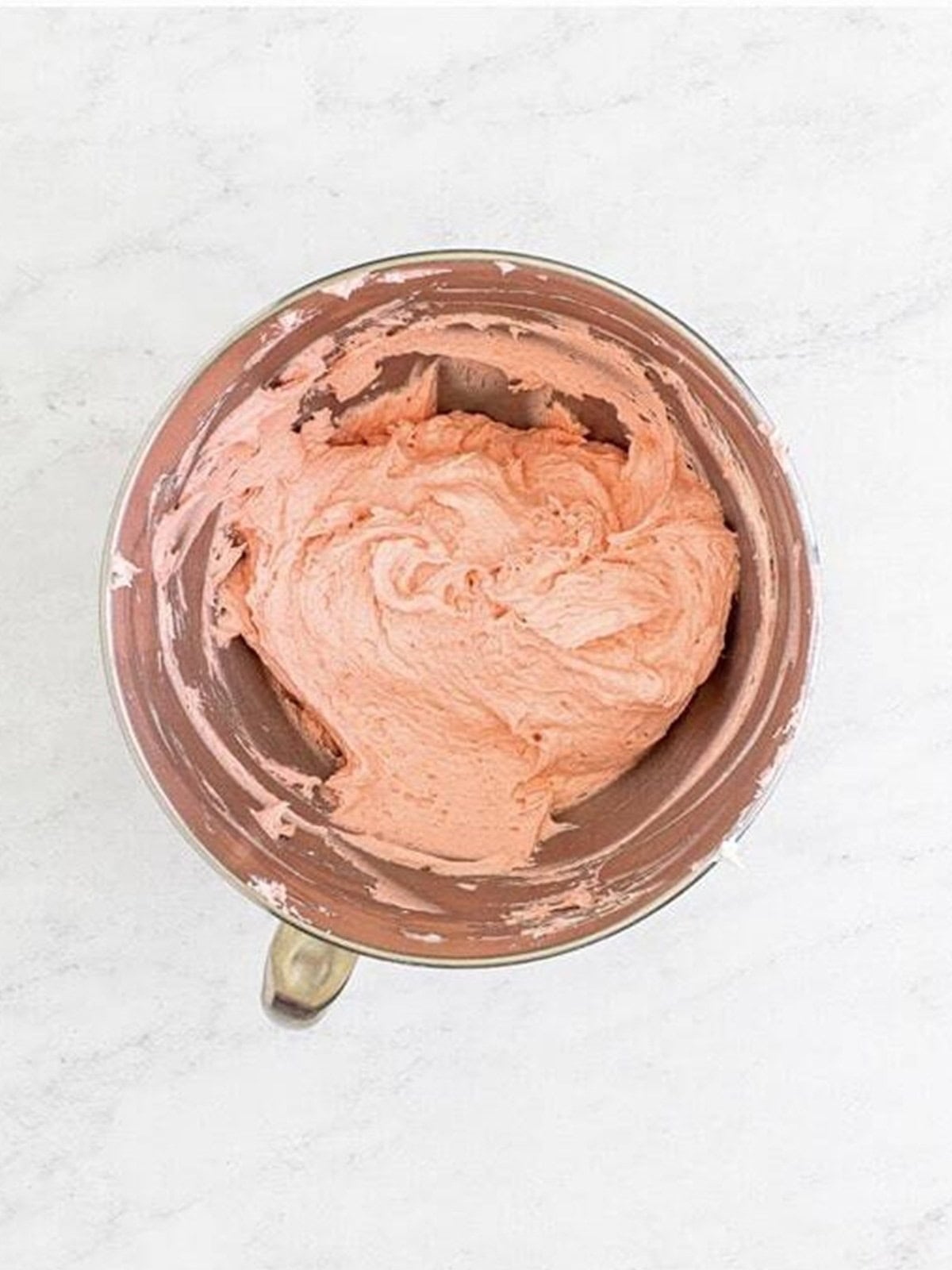 Whipped pink strawberry buttercream in a stand mixer bowl for frosted brownies.