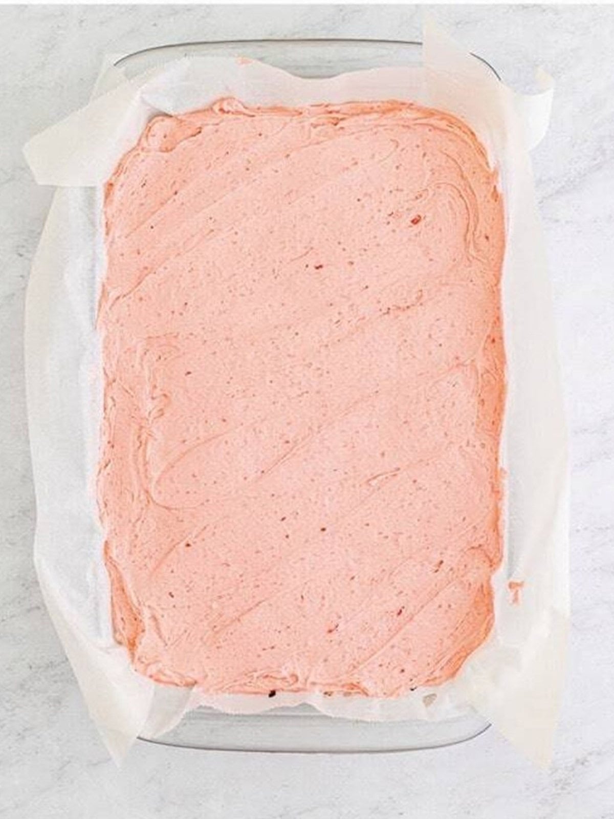 Strawberry buttercream spread evenly over the cooled brownie slab.