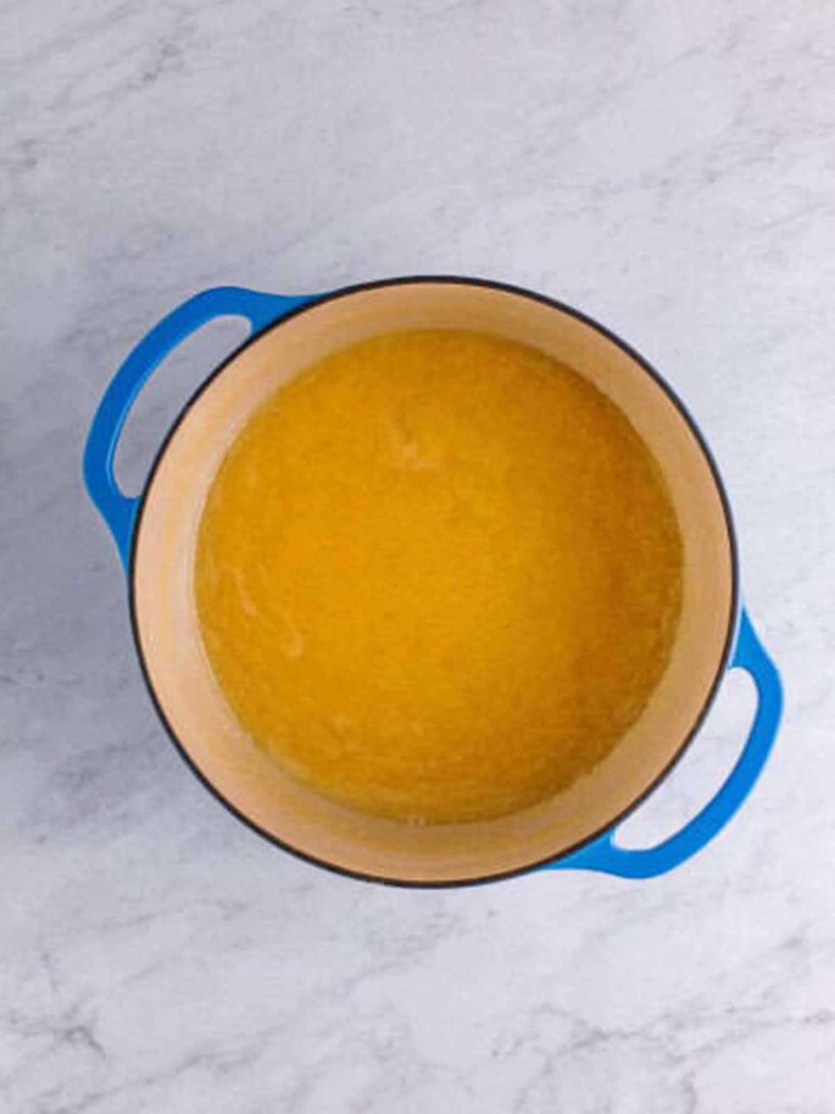 Sugar, evaporated milk, butter, and salt boiling in a dutch oven while being stirred constantly.