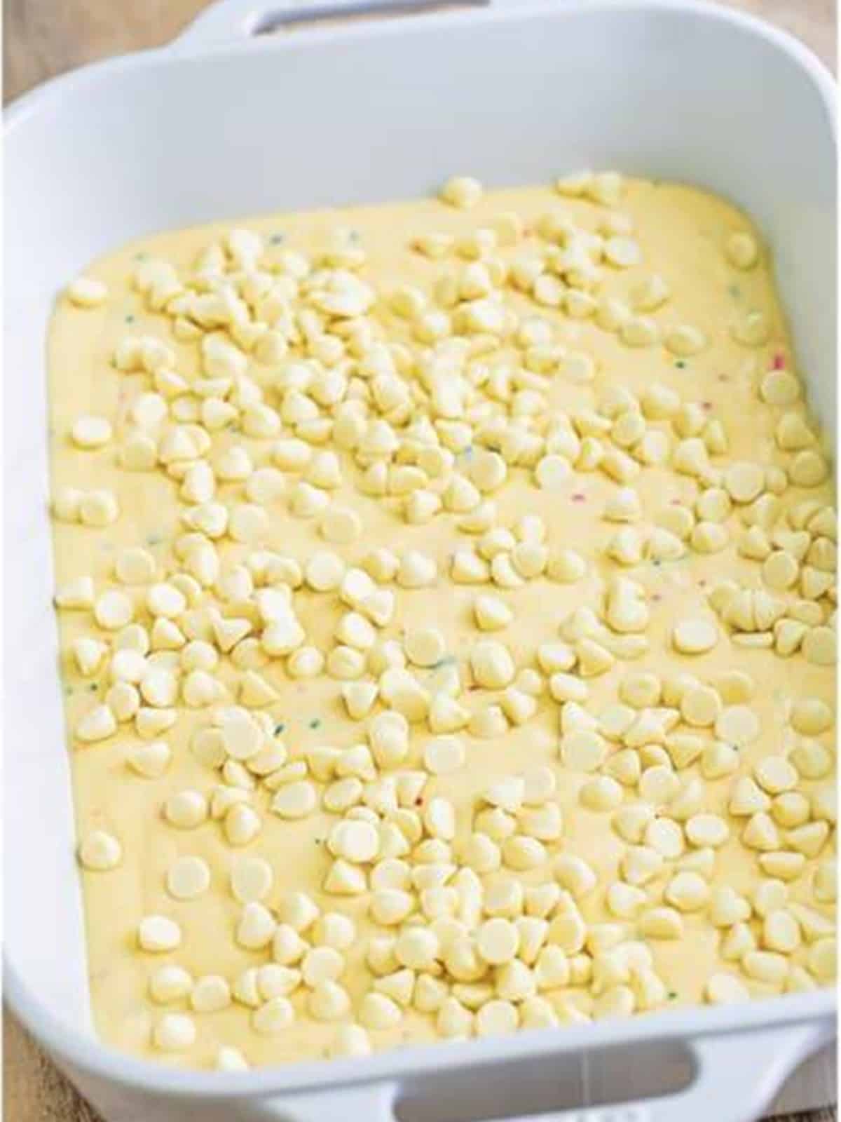 White chocolate chips sprinkled over the funfetti cake batter.