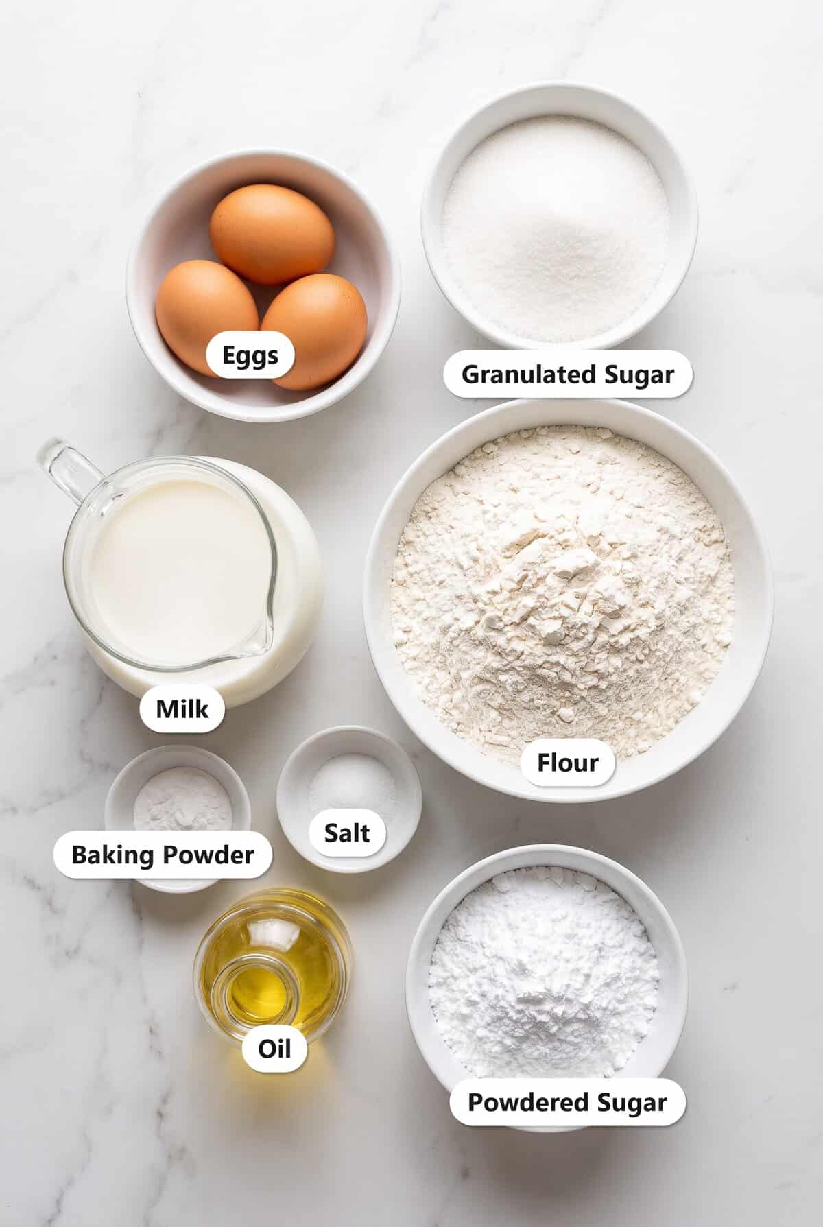 Labeled ingredients to make Funnel Cake: eggs, granulated sugar, milk, flour, baking powder, salt, oil, and powdered sugar.