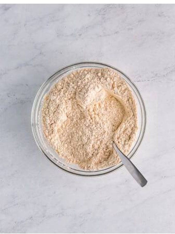Flour, spices, and leavening whisked together in a glass bowl for Gingerbread Cake.
