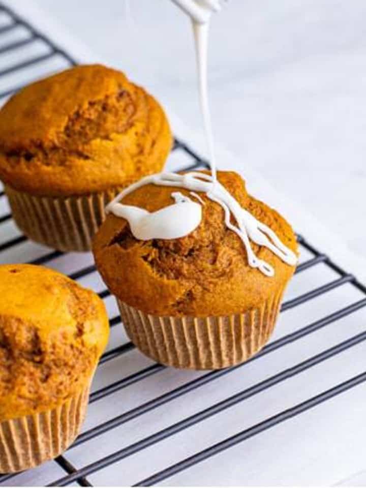 Vanilla glaze drizzled over a gingerbread muffin on a cooling rack.
