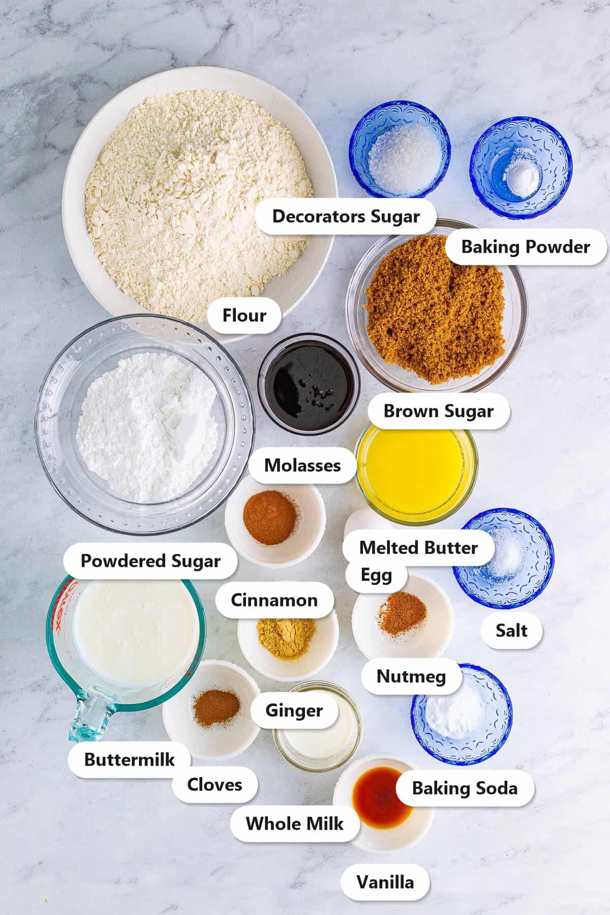 Ingredients to make gingerbread muffins: flour, brown sugar, molasses, melted butter, egg, buttermilk, spices, baking soda, baking powder, salt, vanilla, powdered sugar, and milk for the glaze.