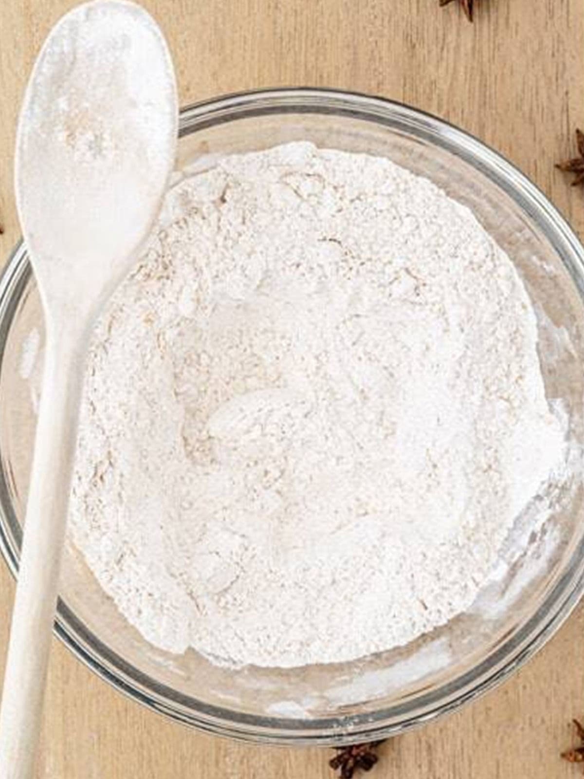 Dry ingredients including flour and spices mixed together in a glass bowl for gingerbread waffles.