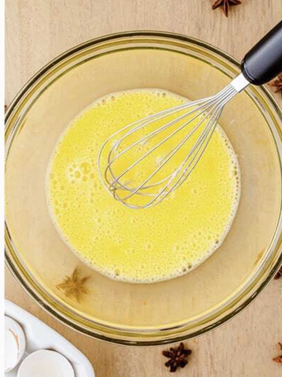 Eggs whisked together in a glass bowl for gingerbread waffle batter.