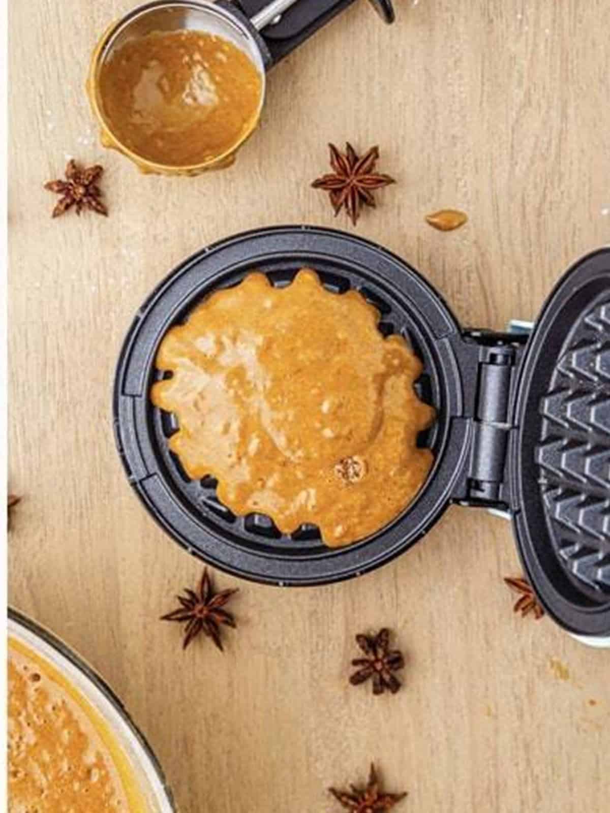 Gingerbread waffle batter cooking in a waffle iron until golden brown.