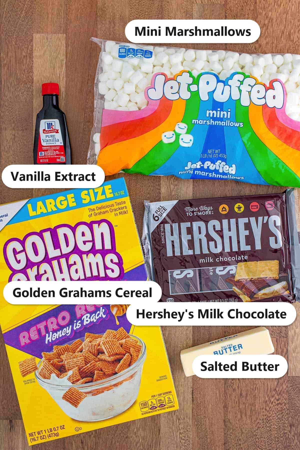 Labeled ingredients for golden grahams smores bars including Golden Grahams cereal, mini marshmallows, Hershey's milk chocolate bars, salted butter, and vanilla extract.
