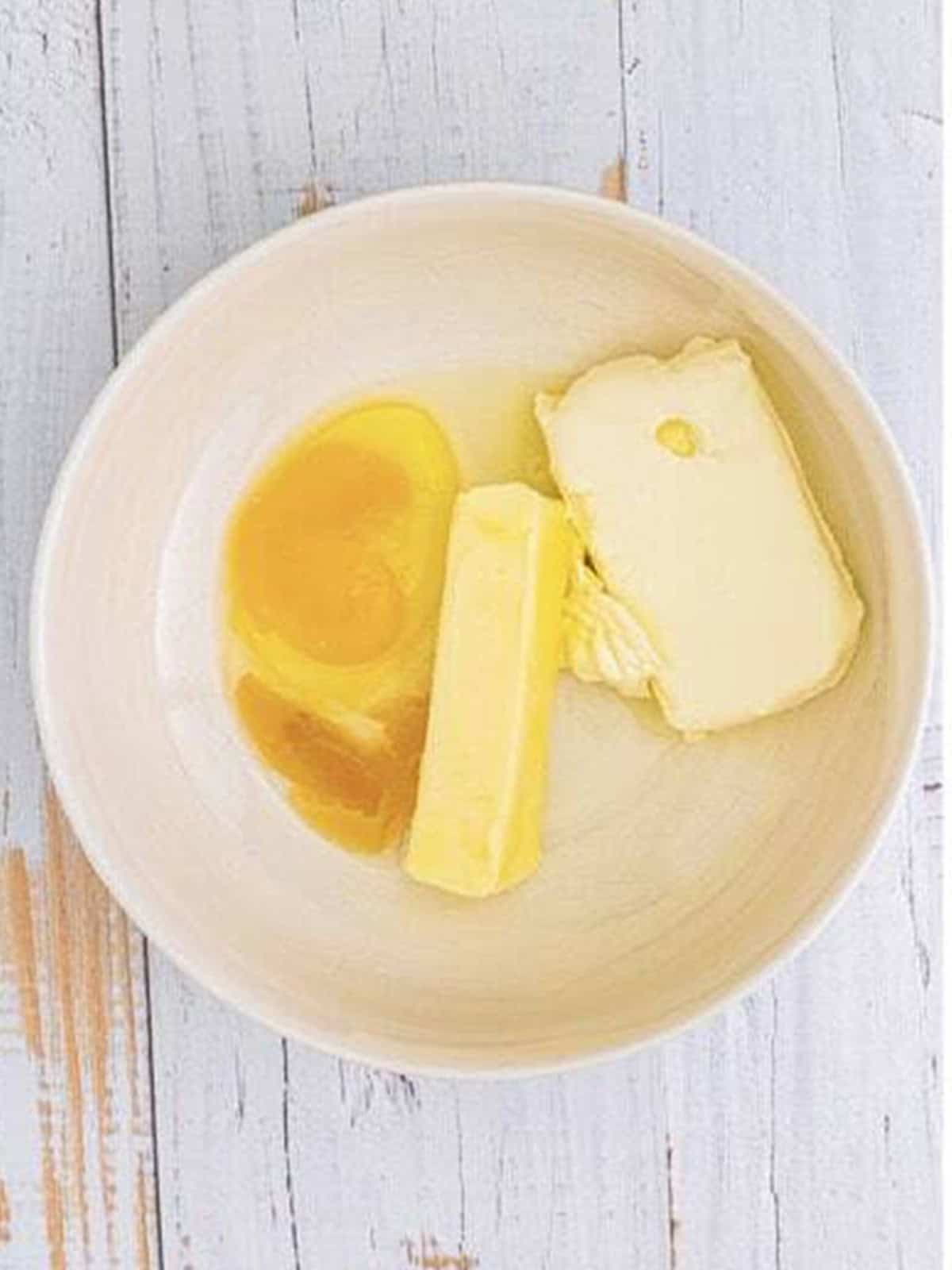 Cream cheese, butter, egg, and vanilla in a bowl to cream together for gooey butter cookies.