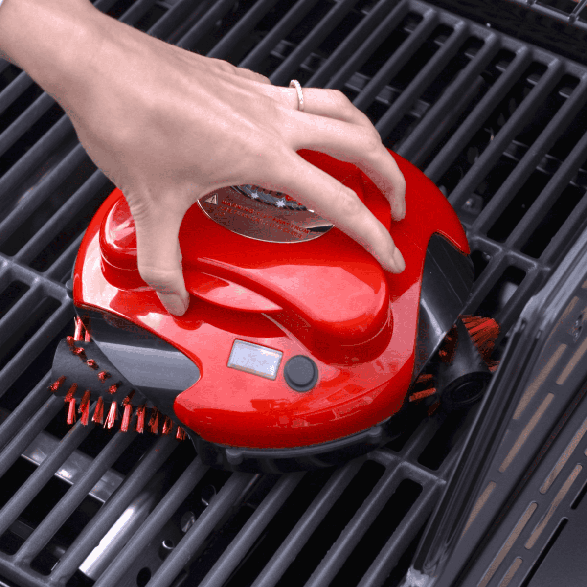Red Grillbot automatic robot grill cleaner sitting on grill grates