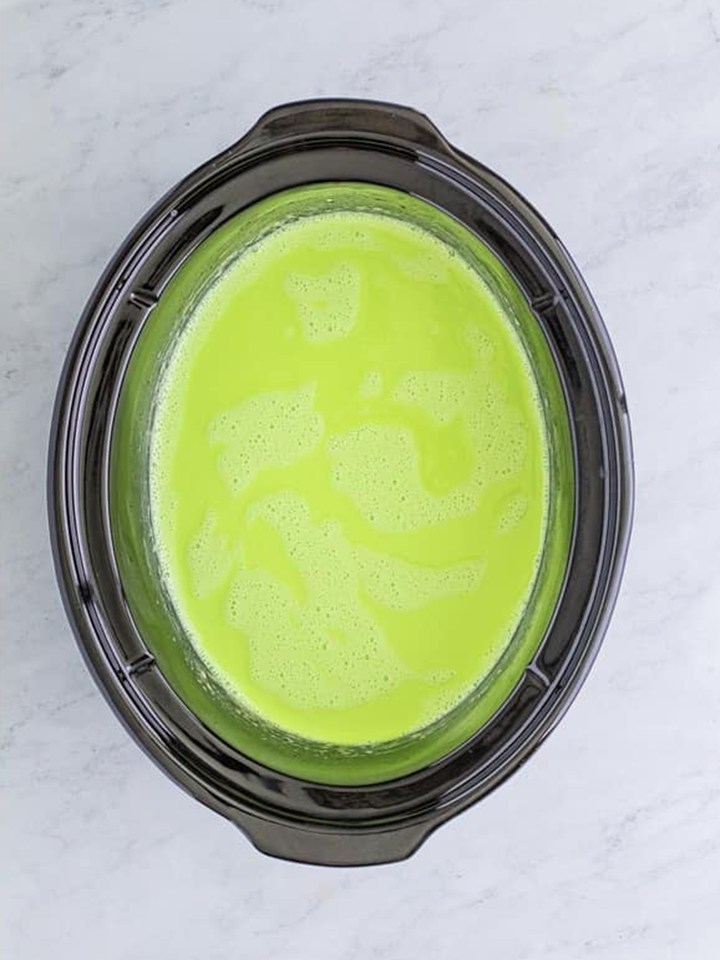 Grinch hot cocoa tinted bright green in the slow cooker and ready to serve.