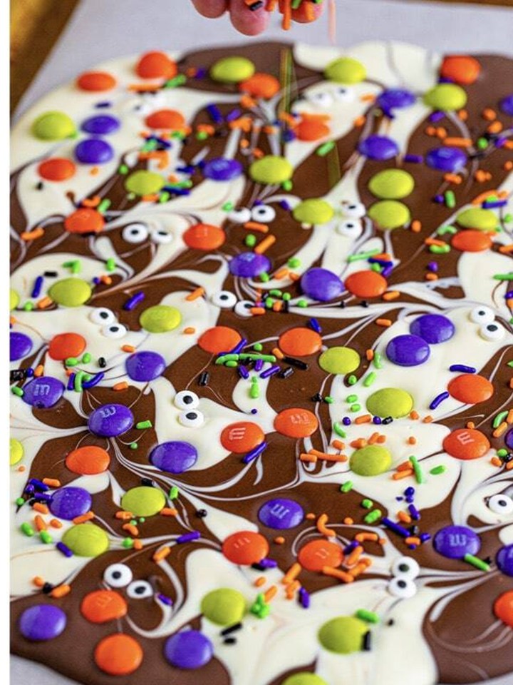 Halloween M&Ms, sprinkles, and candy eyeballs pressed over the swirled chocolate bark.
